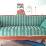 Tapicer robi w warsztacie zieloną sofę w paski.