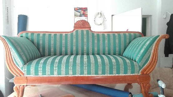 Tapicer robi w warsztacie zieloną sofę w paski.