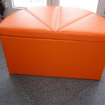 Pomarańczowe pudełko tapicerskie na podłodze wyłożonej kafelkami.